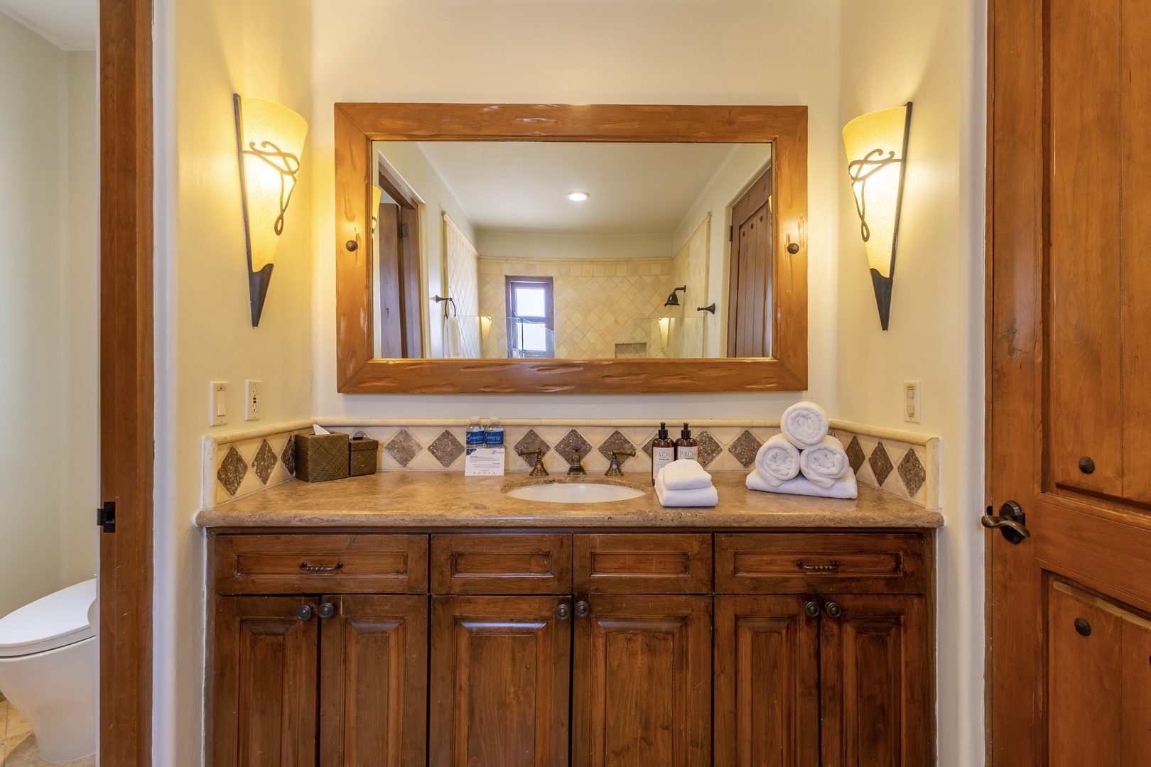Elegant bathroom with warm wood vanity, diamond-pattern tile backsplash, and soft sconce lighting creates your perfect morning routine space.