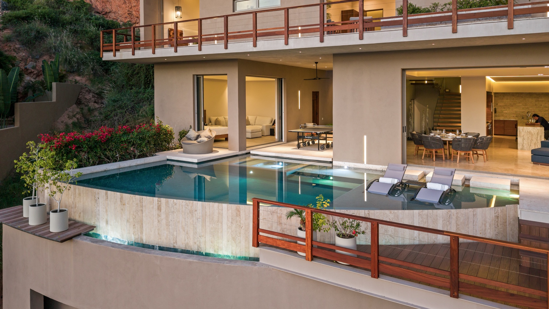 Modern hillside villa featuring multi-level architecture with an infinity-edge pool, spacious terraces, and seamlessly integrated indoor-outdoor living spaces against a lush tropical backdrop.