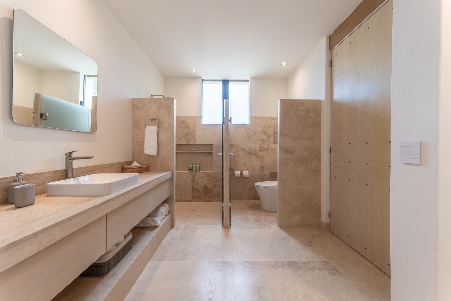 Step into your serene en-suite sanctuary, where warm stone and light wood create a spa-like haven. A spacious walk-in shower, dual vanities, and abundant natural light make mornings feel effortless.