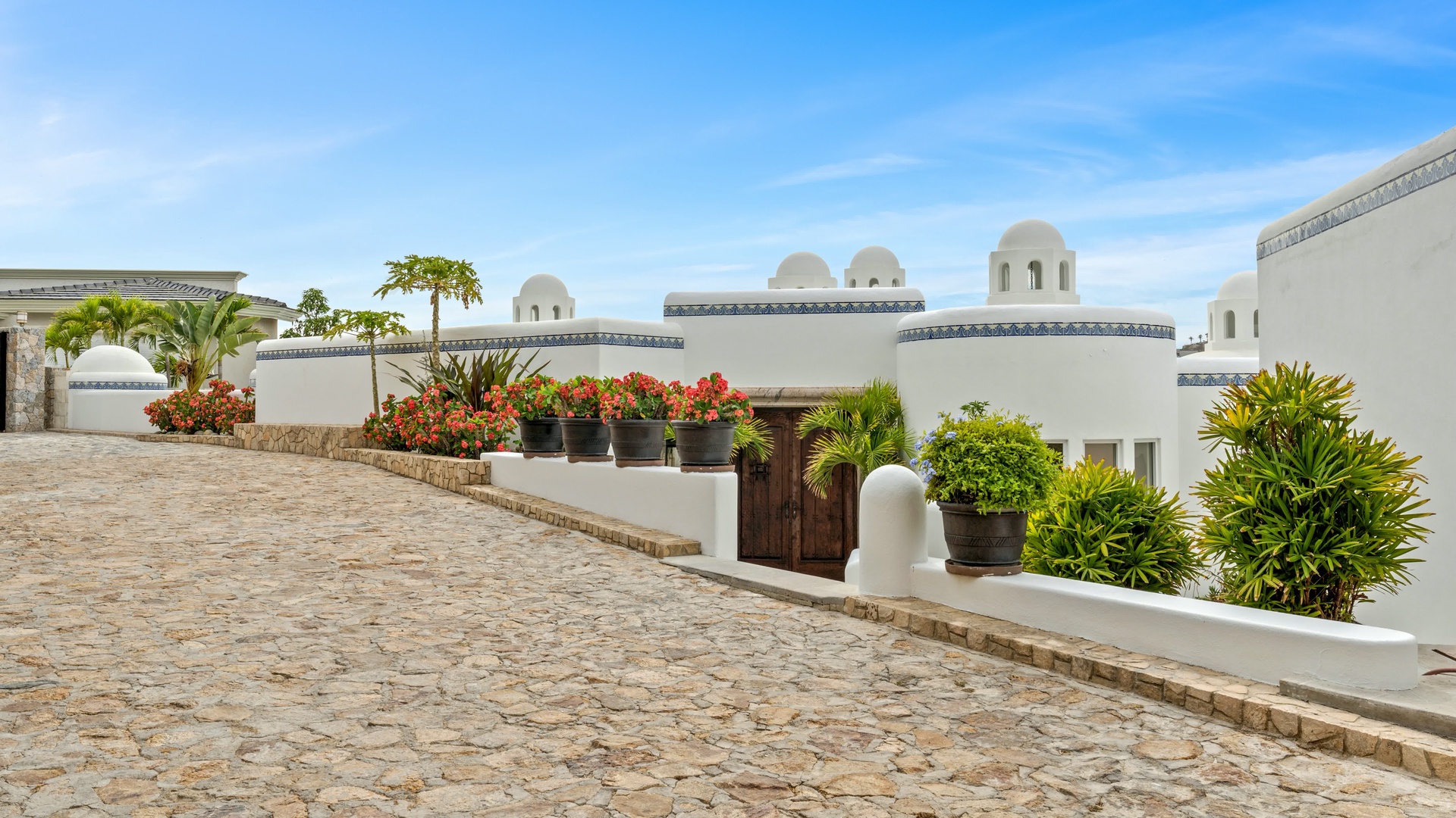 Mediterranean-style resort buildings with distinctive domed architecture and vibrant tropical landscaping create an elegant arrival experience.