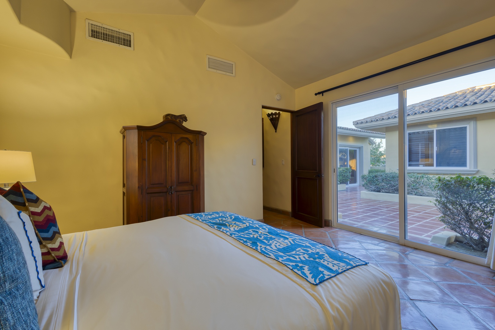 Your cozy bedroom features rustic charm with sliding glass doors opening to a private courtyard, perfect for morning coffee in peaceful surroundings.