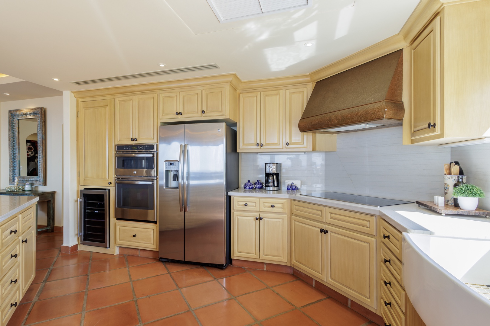 Step into a fully equipped kitchen with stainless steel appliances, ample counter space, and warm terracotta floors—your home base for preparing meals and morning coffee.