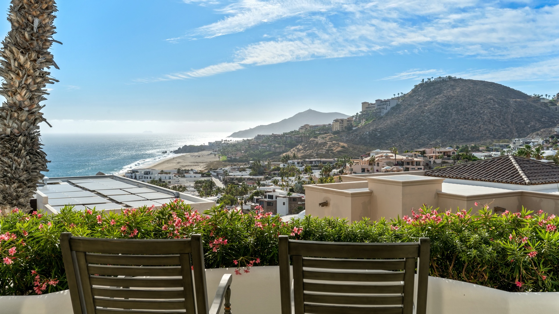 Stunning coastal panorama from elevated terrace showcases dramatic mountainous coastline and sparkling ocean waters.