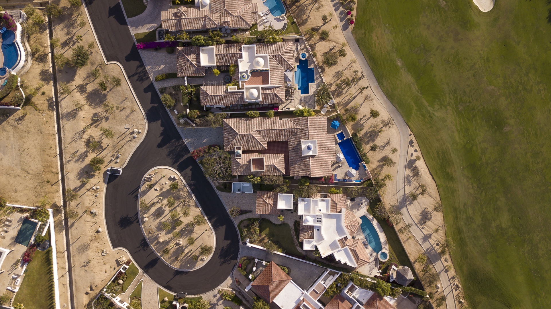 Aerial view of residential community with luxury homes, private pools, and open green spaces nearby.