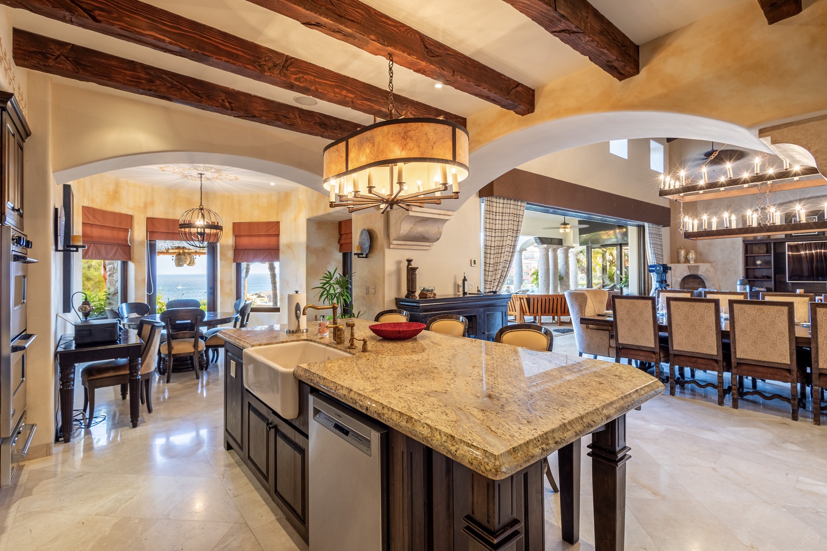 Your gourmet kitchen flows seamlessly into elegant dining and lounge areas, all framed by rustic wood beams and arched windows overlooking stunning water views.