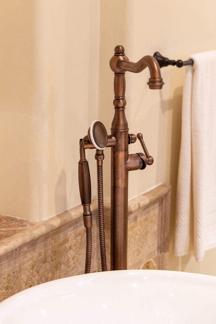 Elegant antique copper fixtures bring timeless character to your private bath, where a handheld shower and luxurious tub await your relaxation.