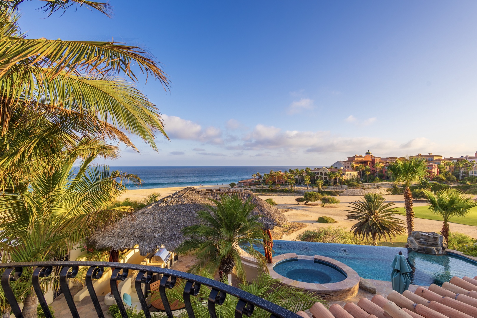 A stunning coastal property set along pristine beachfront, framed by swaying palms and lush landscaping. The resort overlooks golden sand, turquoise waters, and manicured grounds featuring pools and shaded palapas.