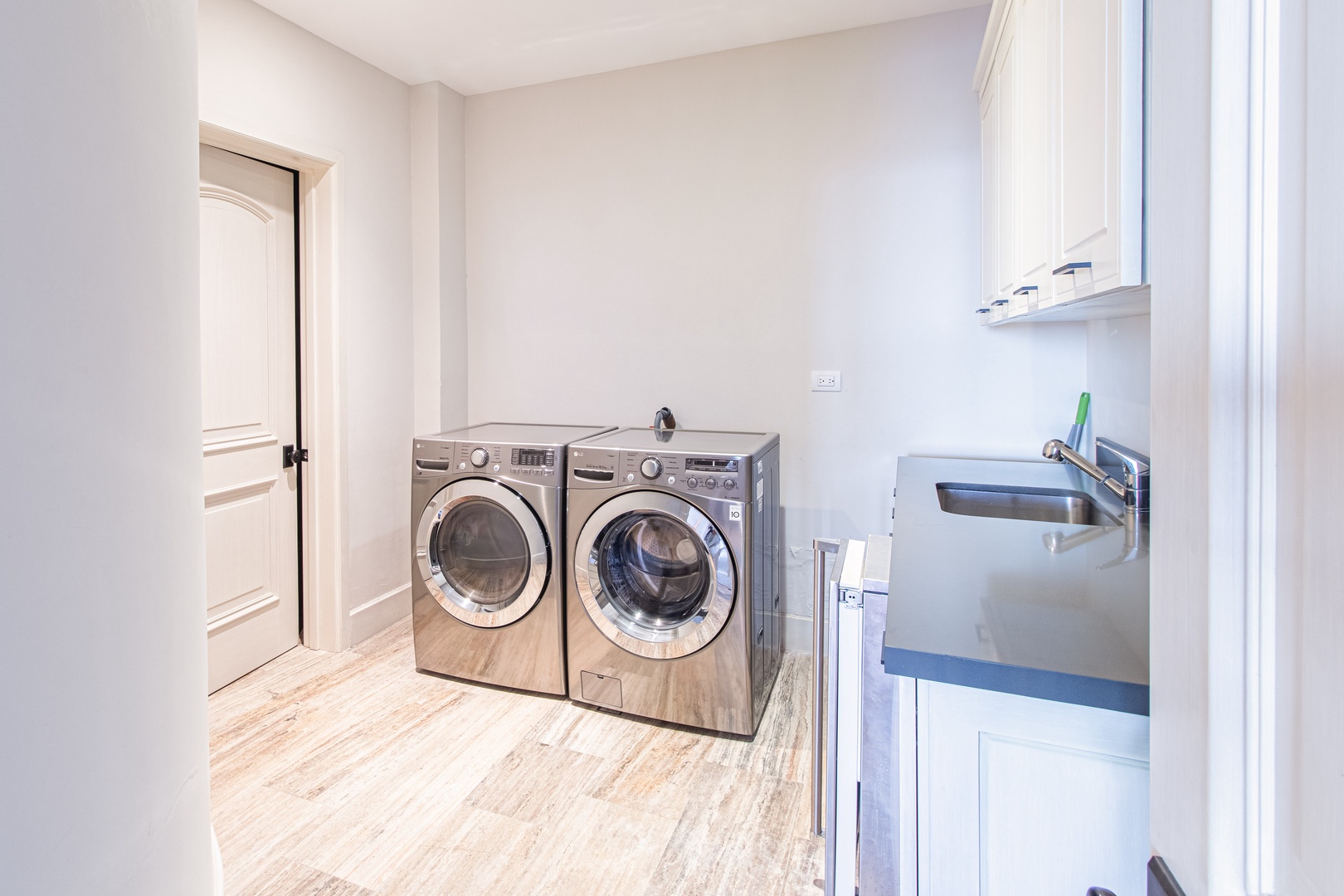 Your dedicated laundry room features side-by-side washer and dryer, a convenient sink, and plenty of cabinet storage to keep essentials organized.