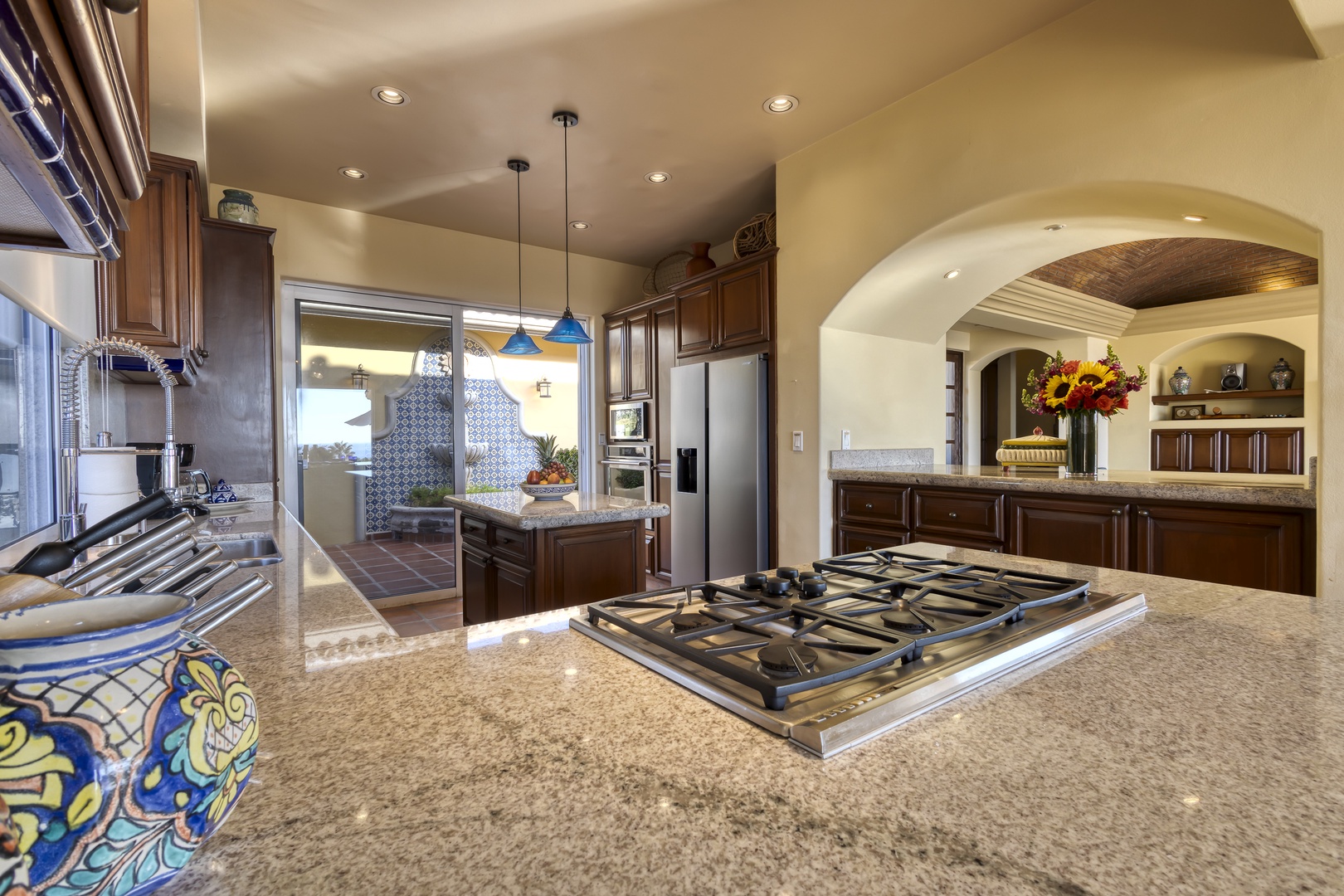 Cook in your spacious gourmet kitchen featuring granite countertops, professional-grade gas range, and elegant archway leading to your dining area.