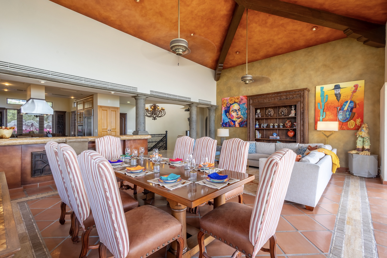 Gather around this inviting dining table where your group can share meals beneath soaring wooden ceilings. Vibrant artwork and warm terracotta tiles create a welcoming atmosphere for memorable moments together.
