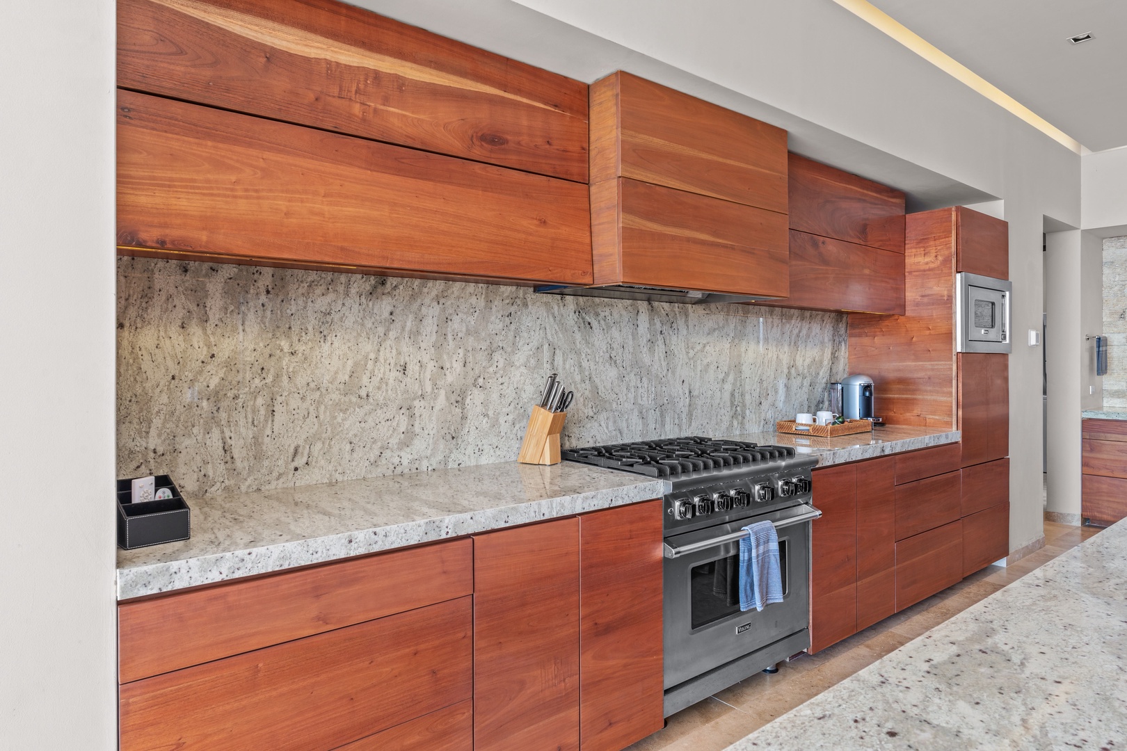 Your chef's kitchen awaits with elegant wood cabinetry, gleaming granite counters, and a professional-grade gas range ready for culinary adventures during your stay.