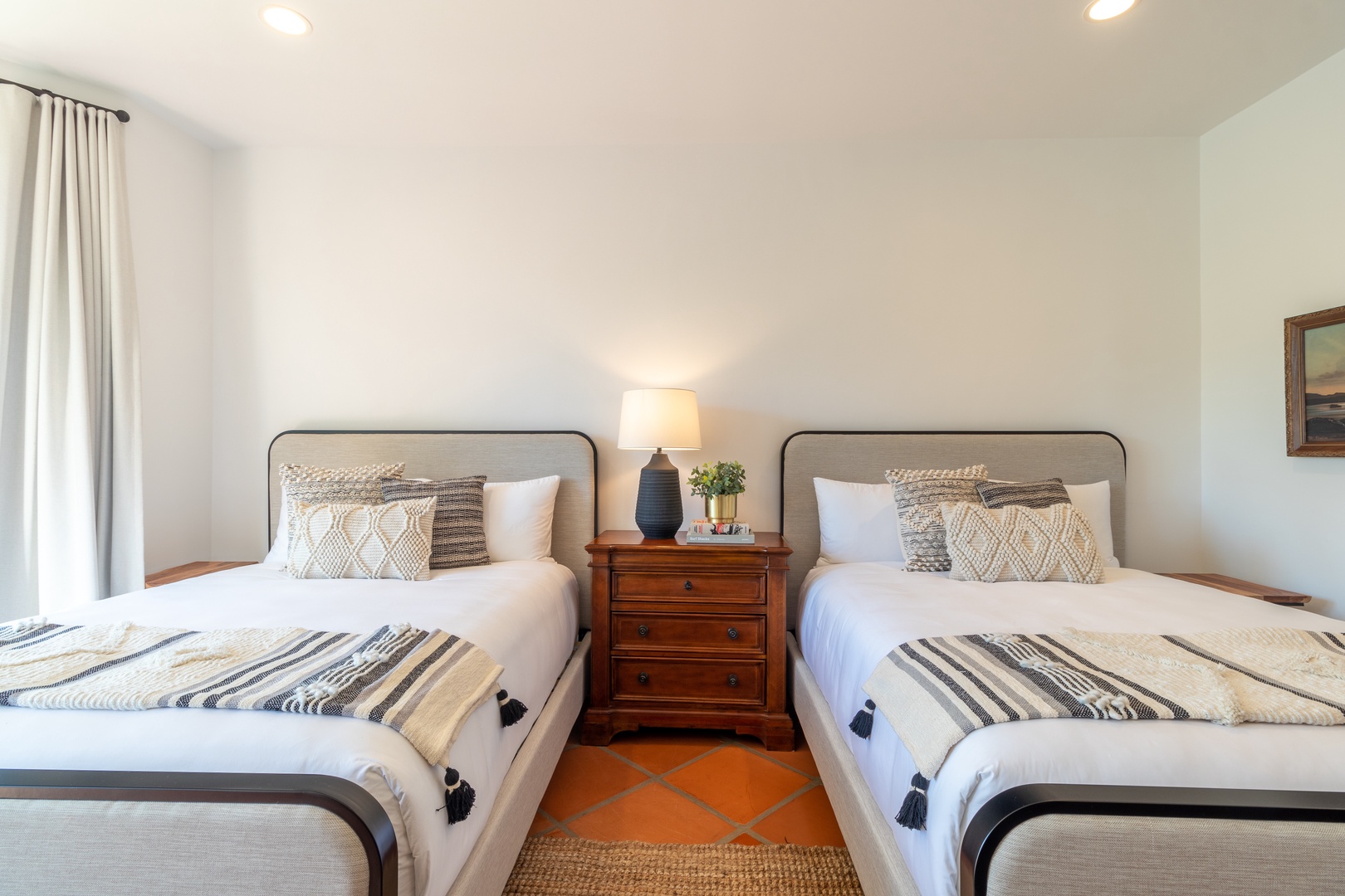 Two comfortable beds await in your serene guest bedroom, styled with cozy linens and warm textures to ensure a restful night's sleep.