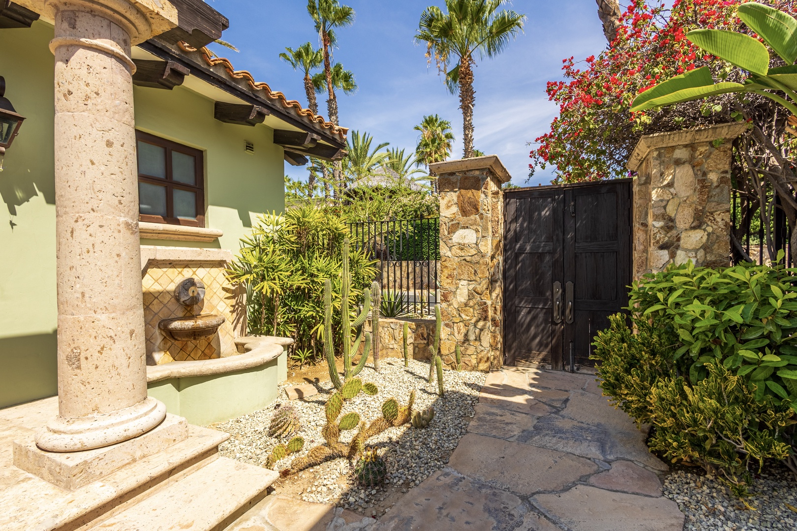 Tropical paradise awaits behind elegant stone gates, where desert gardens meet Mediterranean charm in this private entrance sanctuary.