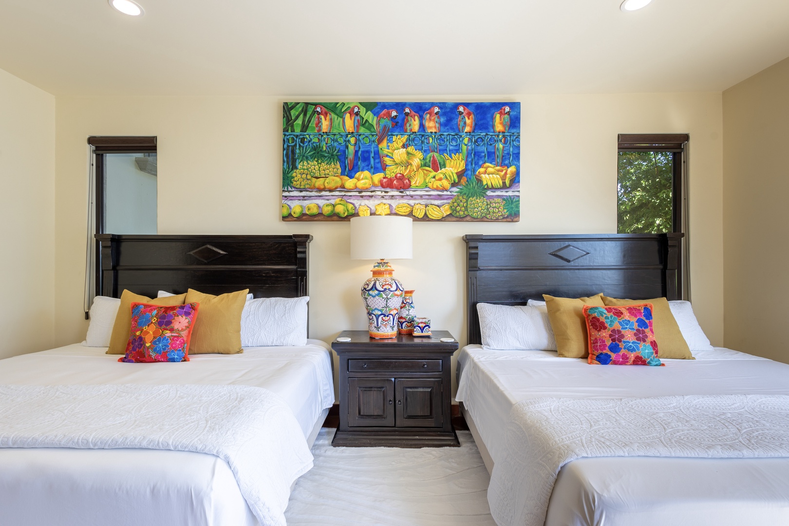 Drift off in comfort with twin beds featuring crisp linens and vibrant Mexican artwork creating a cheerful, restful atmosphere.