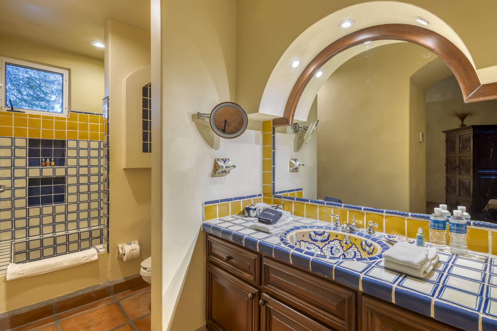 Step into your colorful tiled bathroom featuring a unique archway design, walk-in shower, and charming Mexican-inspired blue and yellow accents throughout.