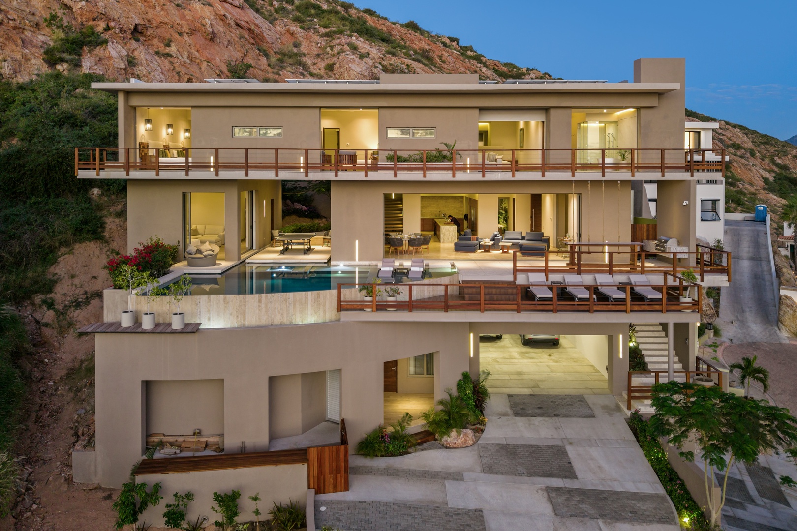 Stunning modern villa nestled into the hillside, offering three expansive levels of contemporary living with wraparound terraces, a sparkling pool, and seamless indoor-outdoor flow.