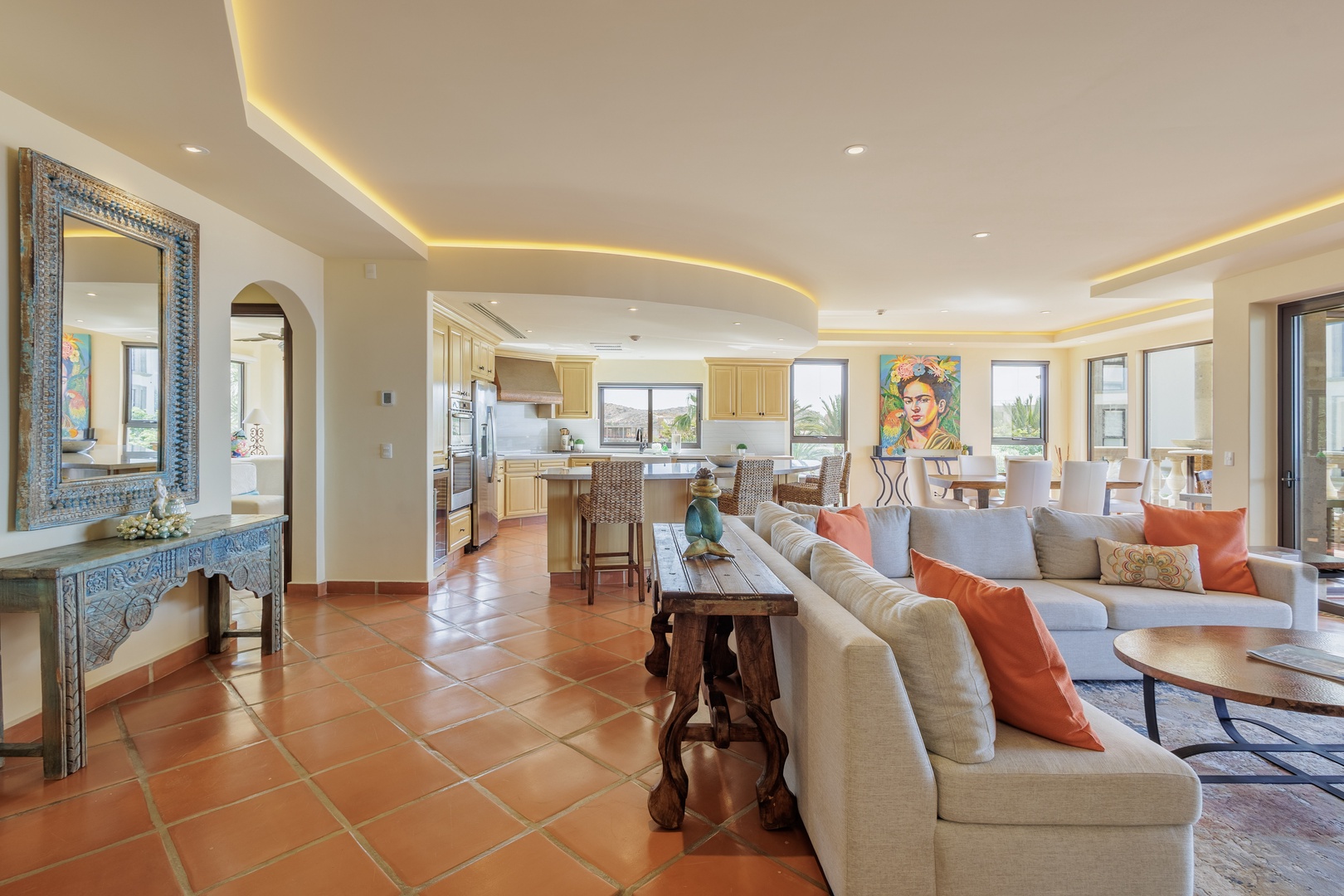 Step into your sunlit open-concept living space where elegant terracotta floors meet coastal charm, inviting you to unwind on plush seating while enjoying vibrant artwork and seamless indoor-outdoor flow.