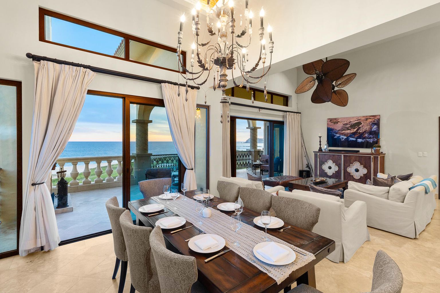 Gather around this elegant dining table where ocean breezes drift through open doors and the chandelier casts warm light over your evening meals. You'll love the seamless flow between indoor comfort and your private terrace overlooking the sea.