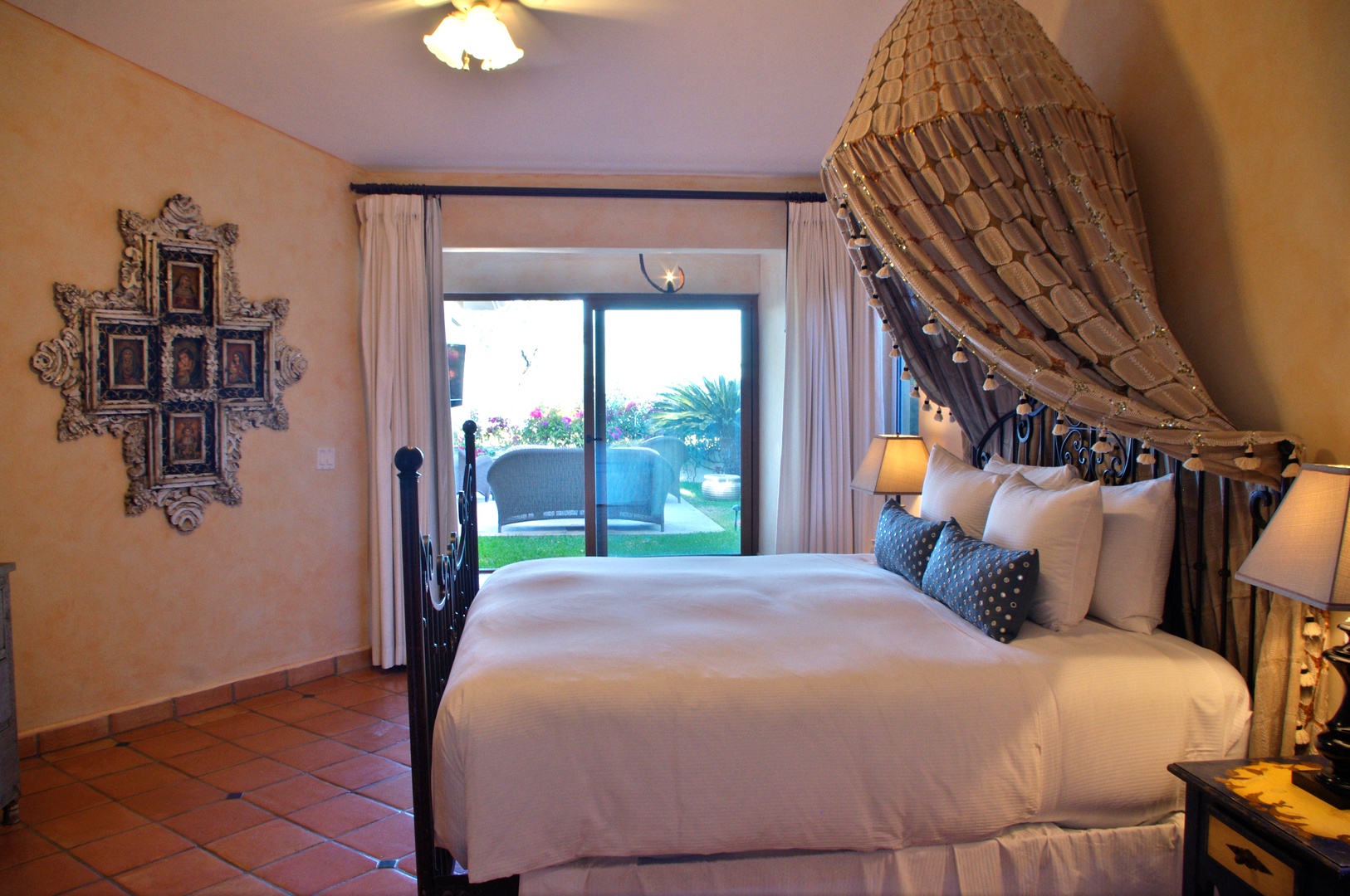 Your tropical retreat awaits with a plush bed dressed in crisp linens and elegant canopy draping. Wake to views of lush palms and inviting outdoor spaces just beyond your private terrace.