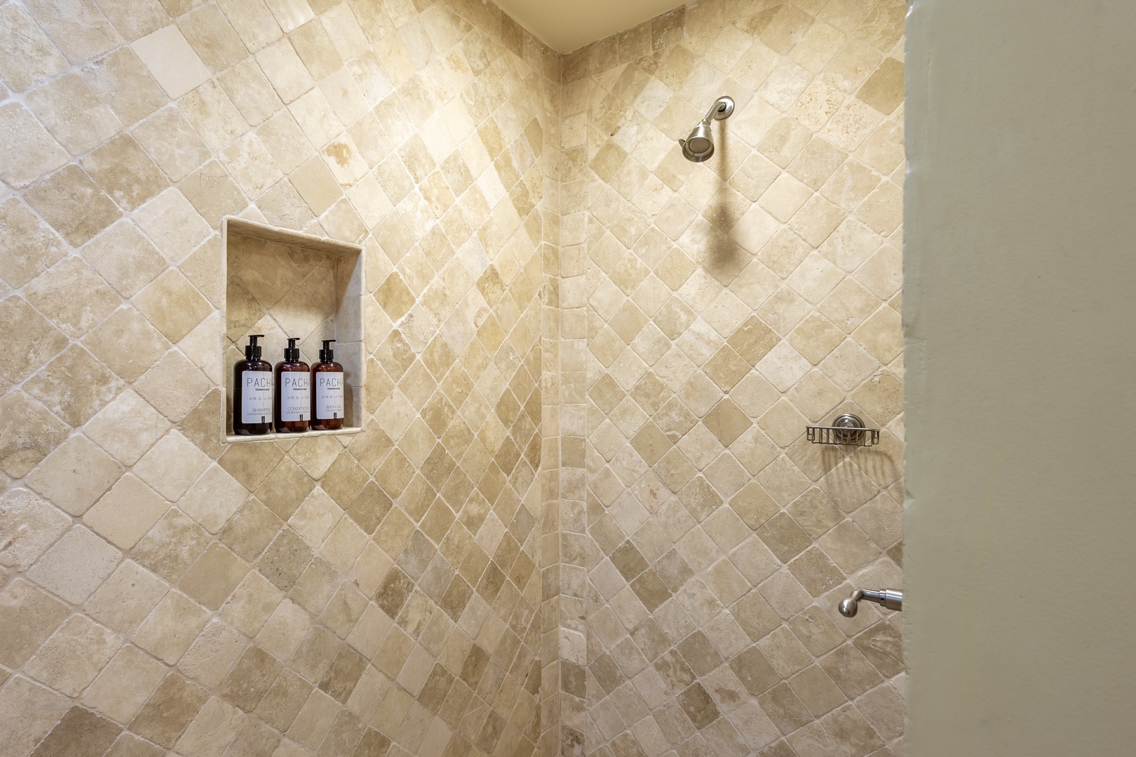 Gorgeous travertine tile envelops your private shower, complete with a built-in niche stocked with luxury bath amenities for a spa-like start to each morning.