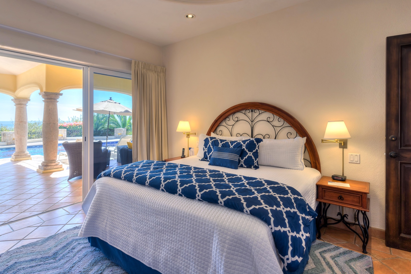 Wake up to stunning views from your elegant bedroom, where blue and white linens create a serene retreat overlooking the terrace.