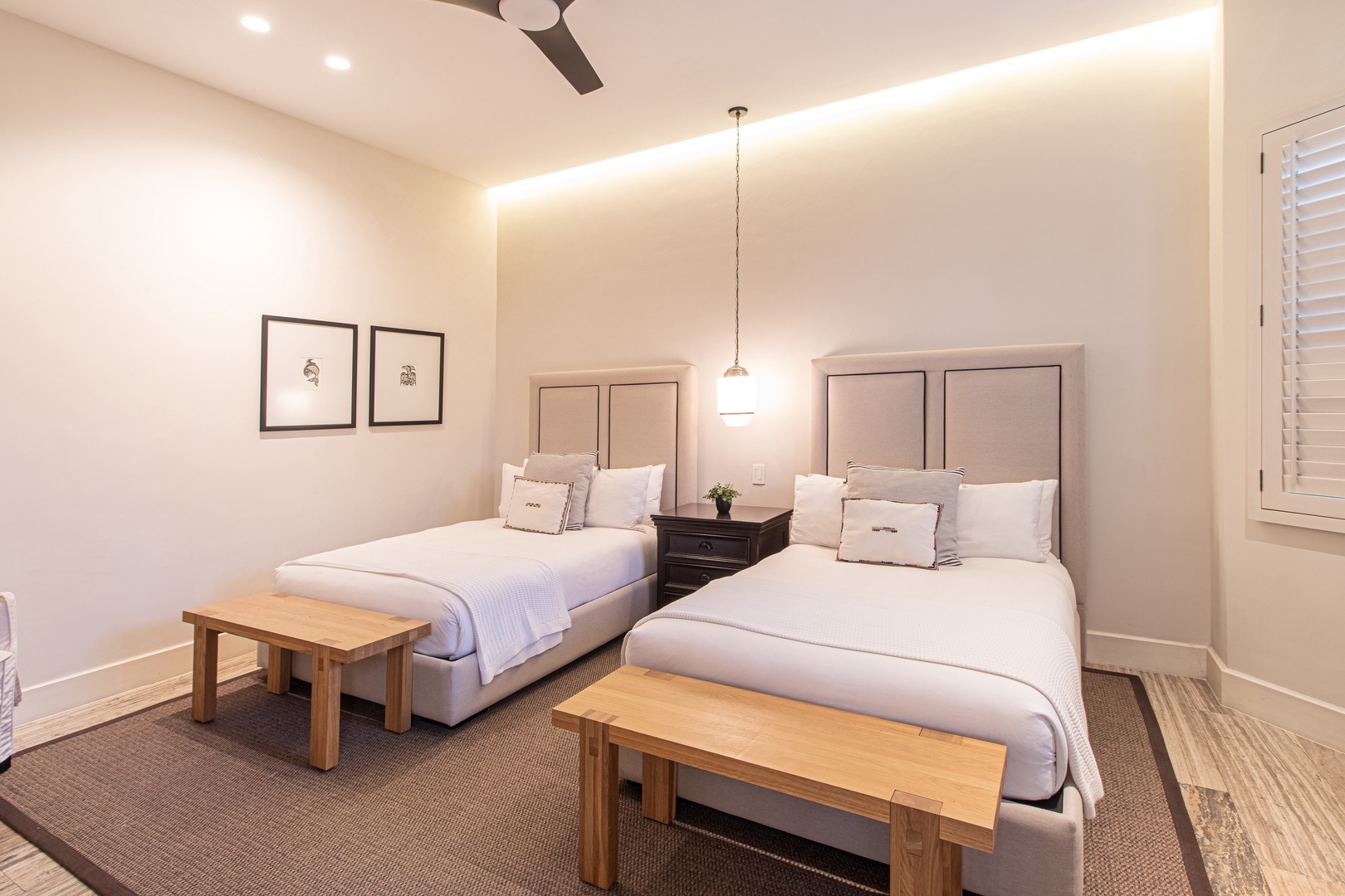 Sink into crisp white linens and modern comfort with two plush queen beds, sleek lighting, and a ceiling fan for your perfect rest.