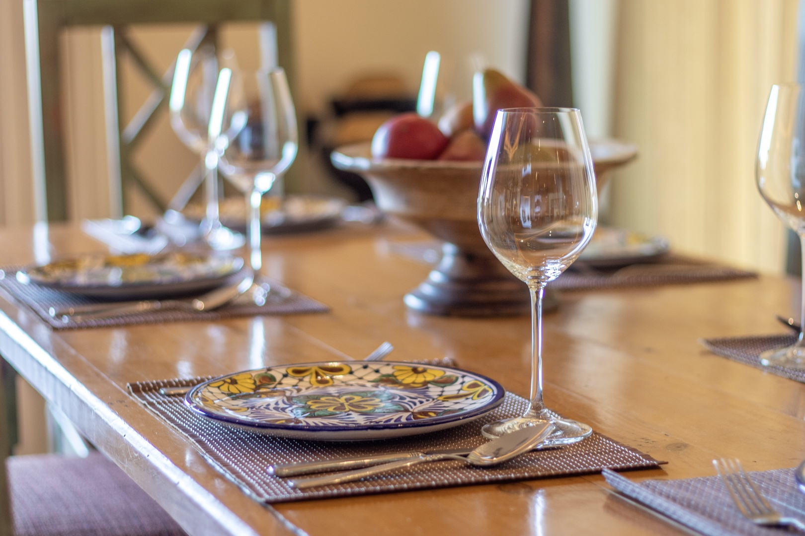 Your beautifully set dining table awaits, with elegant wine glasses, artisan plates, and a warm wooden surface that sets the scene for memorable meals and evenings together.