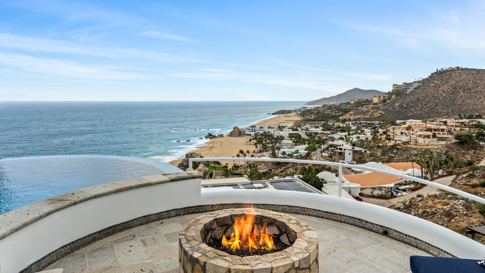Dramatic coastal fire pit with sweeping ocean and beach views creates the perfect evening gathering spot.