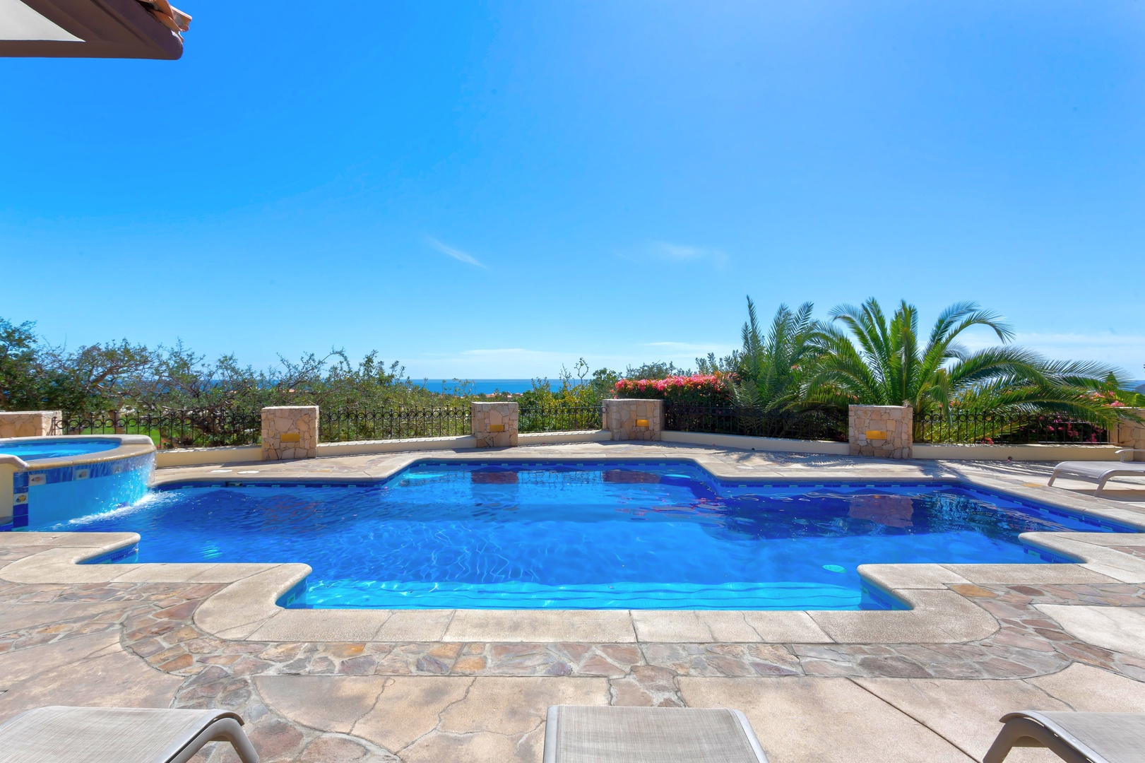 Crystal-clear pool with stunning ocean views and tropical palms creates your perfect paradise retreat.