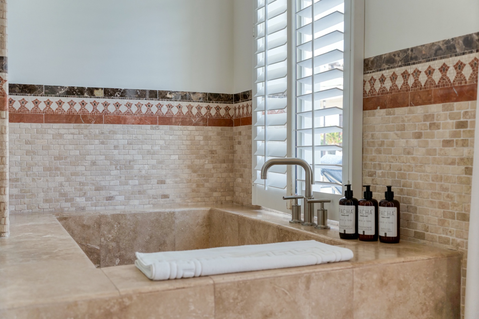 Unwind in your spa-like marble soaking tub with decorative mosaic tiles and luxury bath amenities perfectly arranged for your relaxation.
