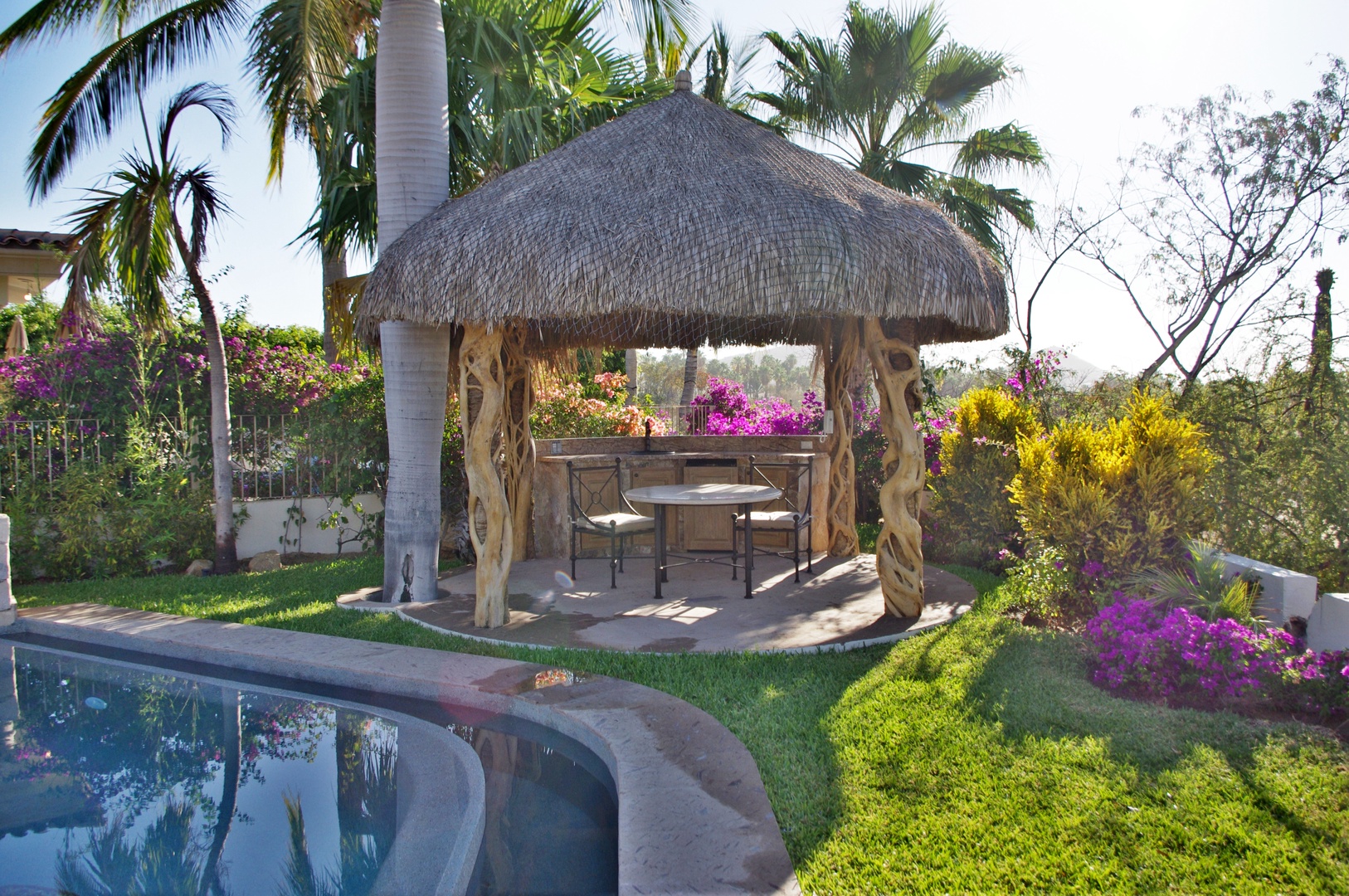 Escape to your private poolside cabana, surrounded by lush tropical gardens with vibrant flowering plants. Relax under the thatched roof while enjoying serene views of palm trees and colorful blooms.