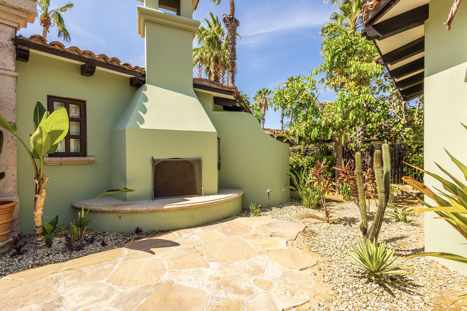 Step into your private courtyard featuring a cozy outdoor fireplace surrounded by lush desert gardens and tropical palms.