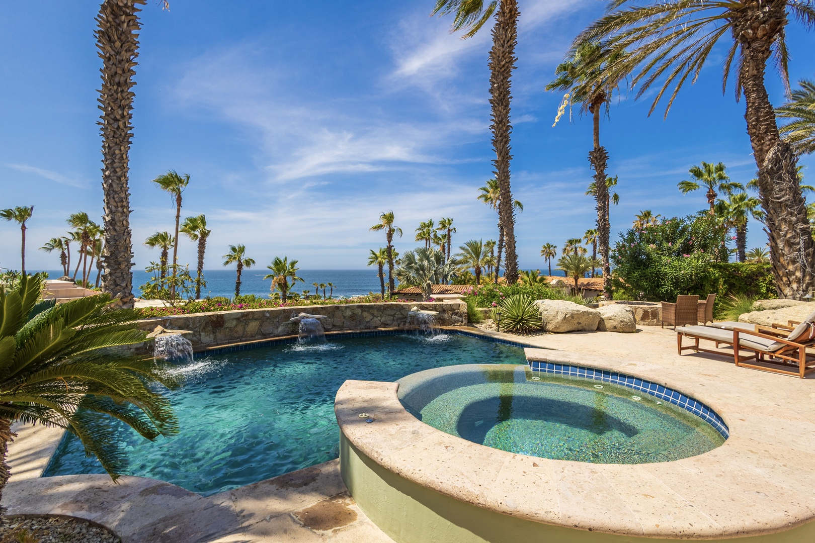 The property's private pool and hot tub sit beneath towering palms, offering a tranquil oasis framed by azure ocean views and tropical landscaping—a secluded paradise designed for ultimate relaxation.