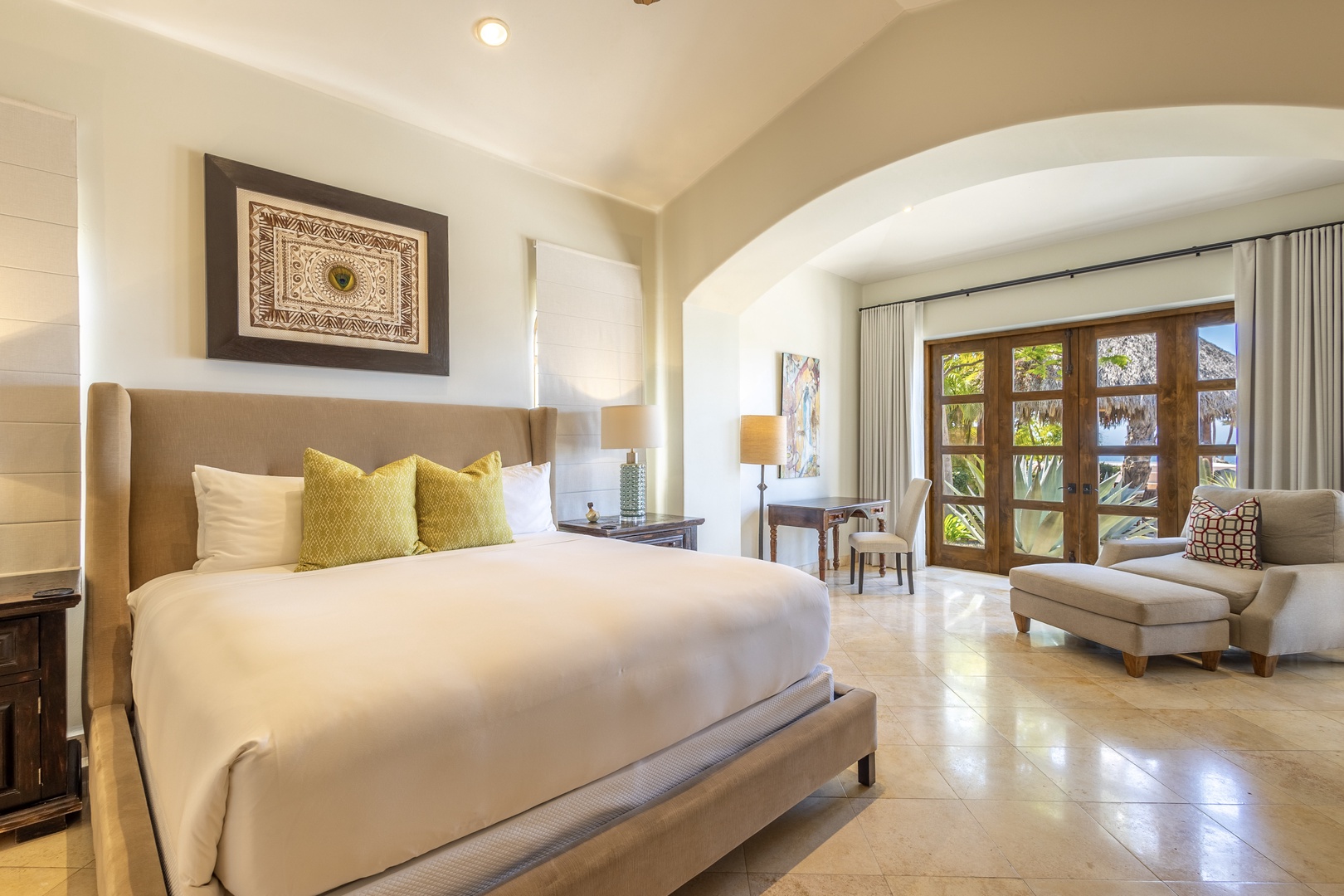 Sink into luxury with crisp linens, golden accent pillows, and your private reading nook by tropical garden doors.