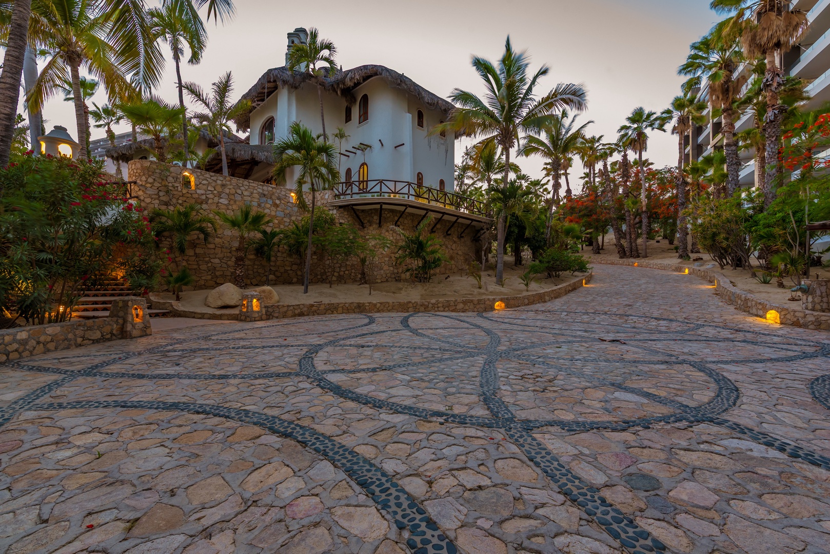 Tropical paradise entrance with stunning stonework courtyard, lush palms, and elegant architecture creating an unforgettable first impression of this unique coastal retreat.