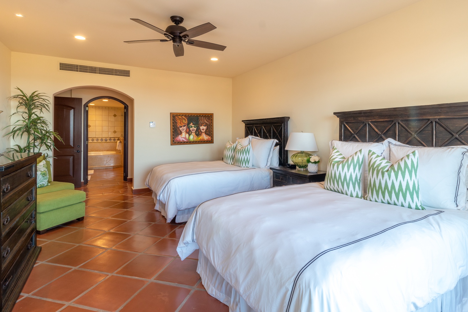 Drift into dreamland on plush beds with crisp linens and pops of vibrant color. Your spacious retreat features warm tile floors, ceiling fan comfort, and an en-suite bath for ultimate relaxation.