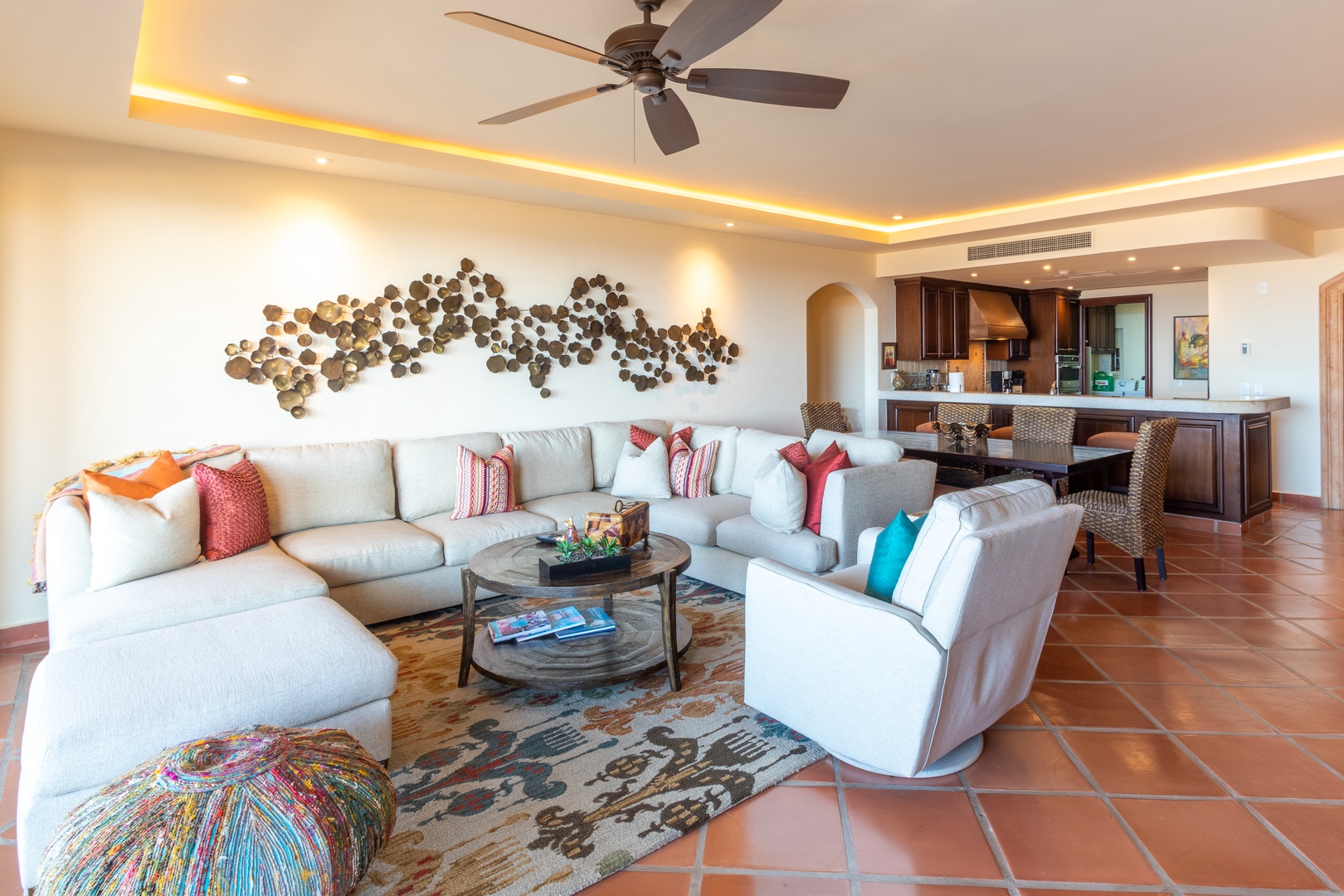 Sink into plush seating beneath artistic wall decor and warm ambient lighting. Your open-plan living and dining space invites relaxation with vibrant accents and seamless flow into the kitchen.