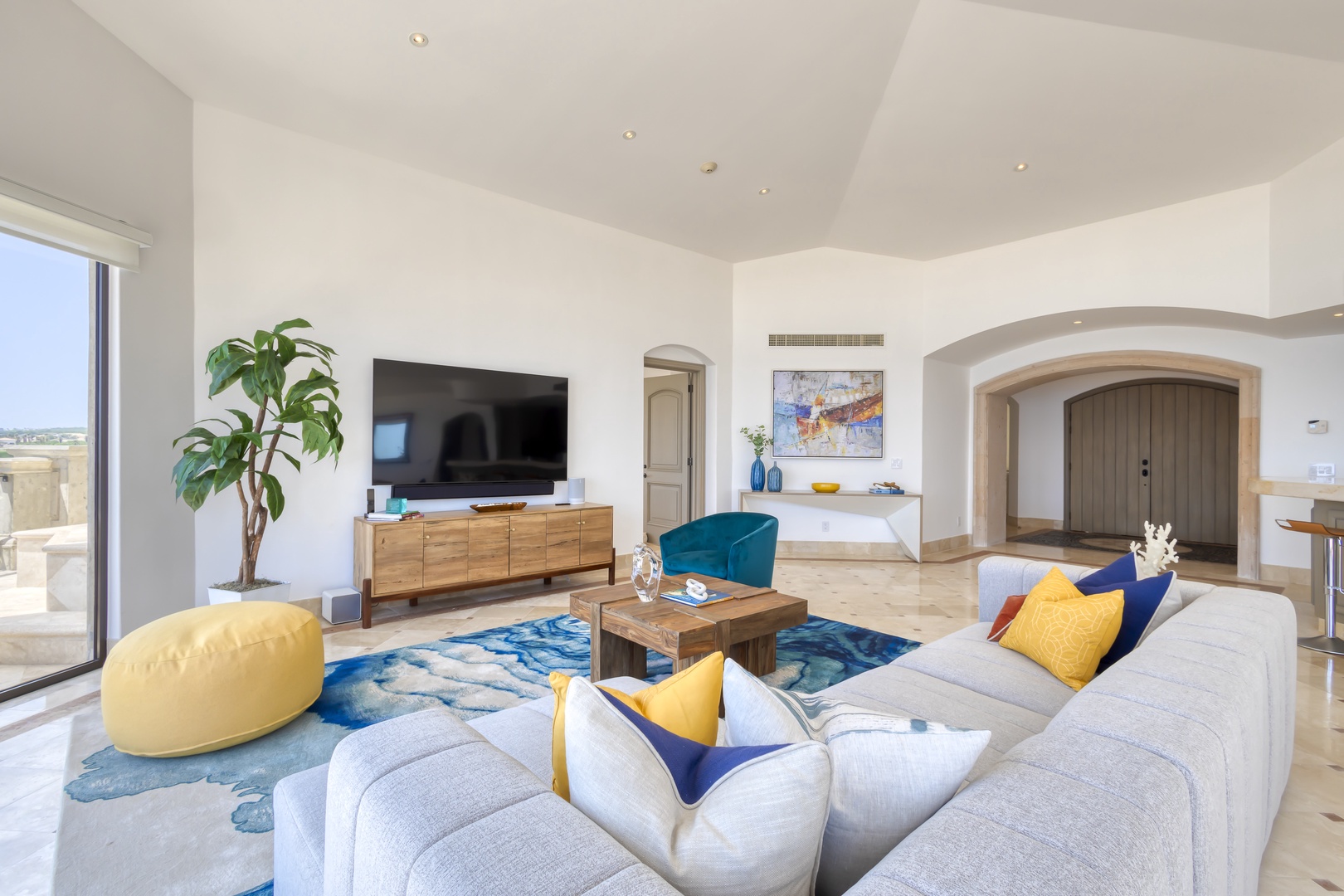 Sink into plush seating with pops of blue and gold while natural light pours in, framing your peaceful escape in this bright, airy living space.