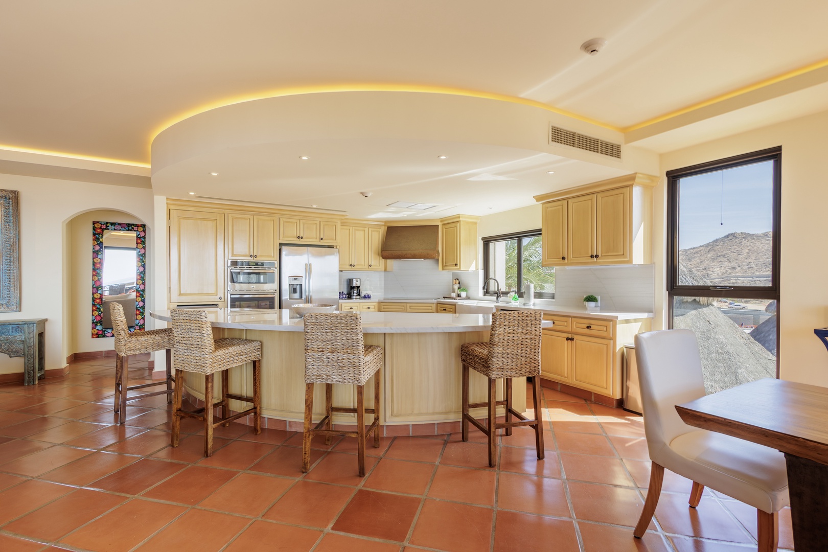 Your gourmet kitchen invites culinary adventures with its spacious island, warm wood cabinetry, and stunning desert views framing the room in natural beauty.