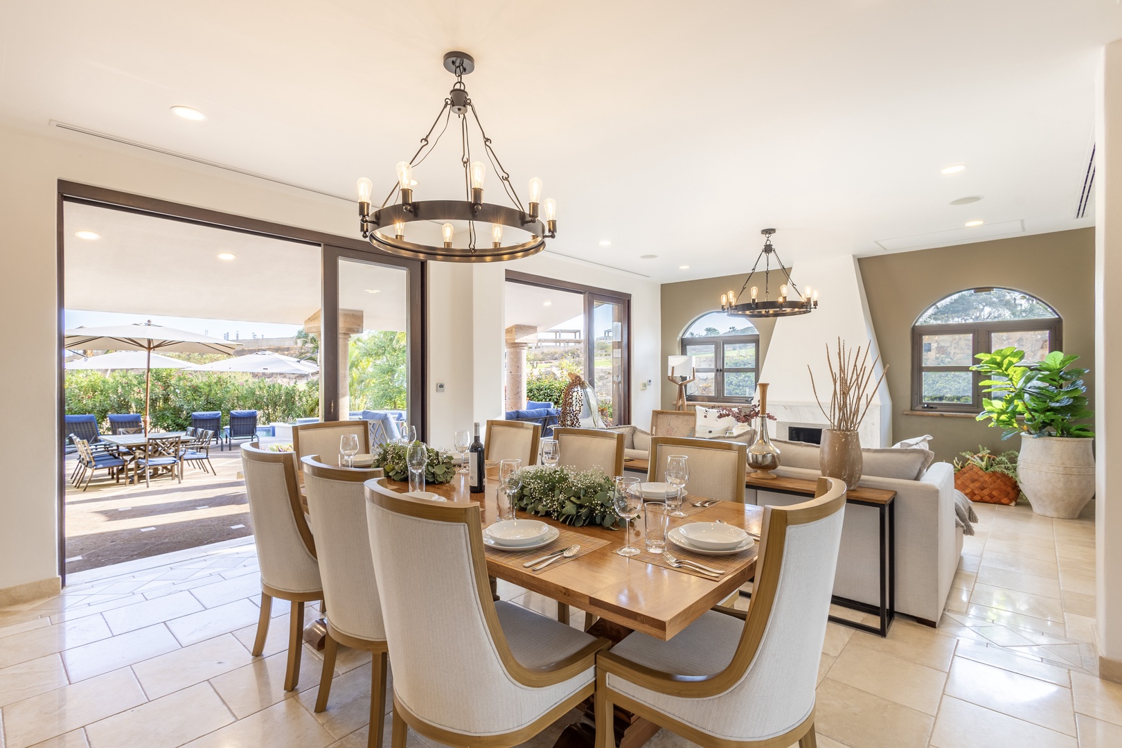 Gather around this elegant dining table where sunlight streams through arched windows, inviting you to savor meals with loved ones in a bright, airy setting that flows seamlessly to your private outdoor patio.