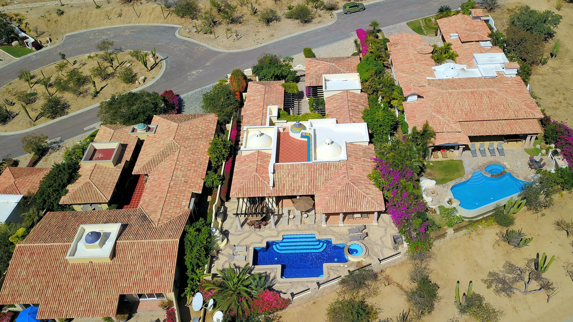 Spectacular aerial view showcases the expansive Mediterranean-style resort with terra cotta rooftops, multiple swimming pools, and lush desert landscaping.