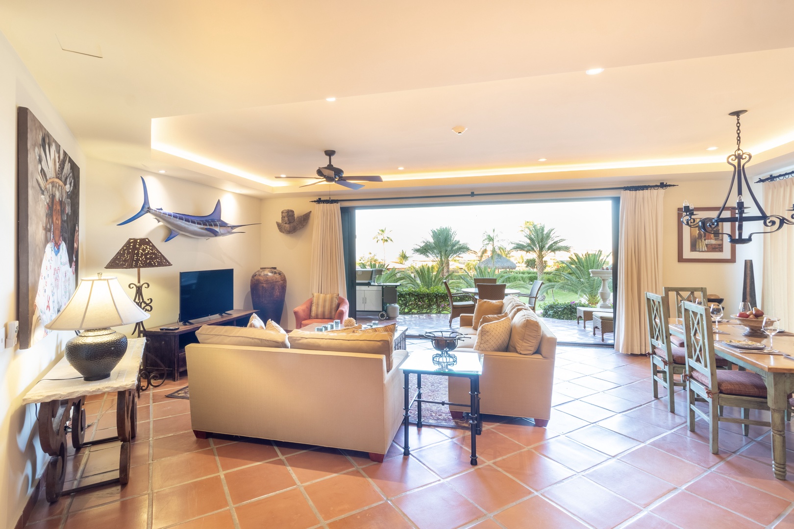 Step into an open-concept living space where warm coastal décor meets breezy tropical views. Relax in the spacious living room, gather at the dining table, then step out to your private patio surrounded by lush palms.
