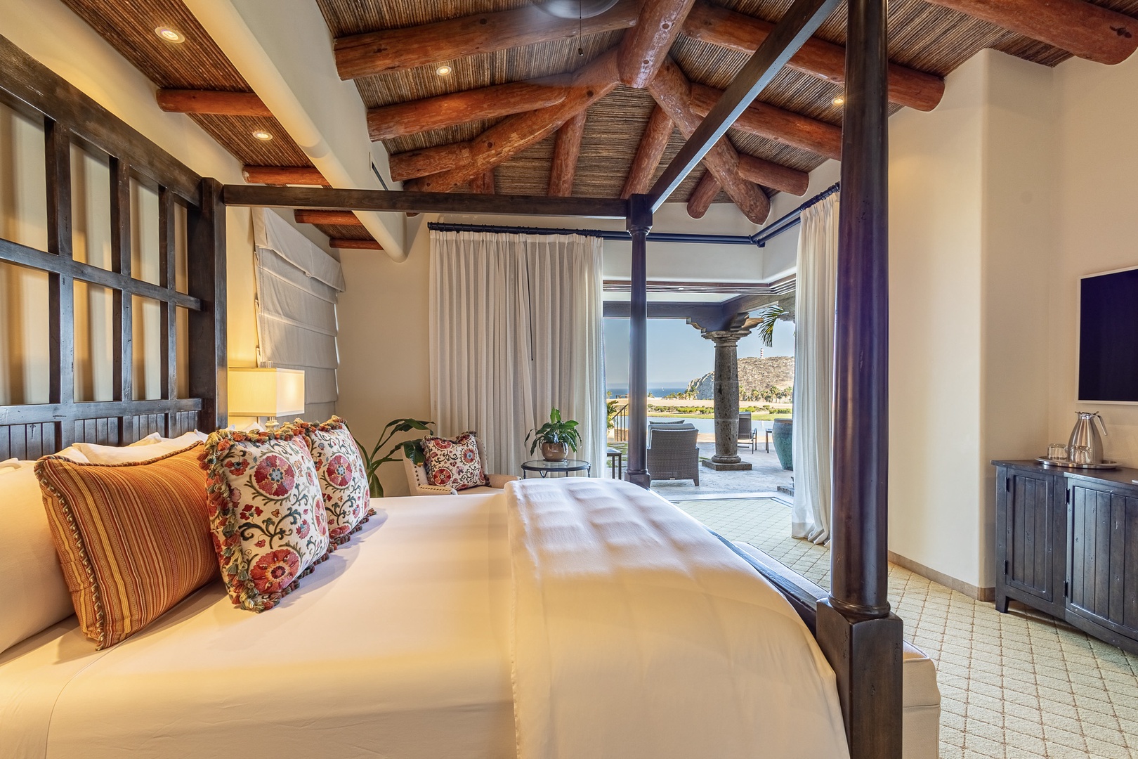 Wake up to stunning views in this elegant bedroom, where exposed beam ceilings and a four-poster bed create your peaceful retreat, with direct access to your private outdoor terrace and pool.