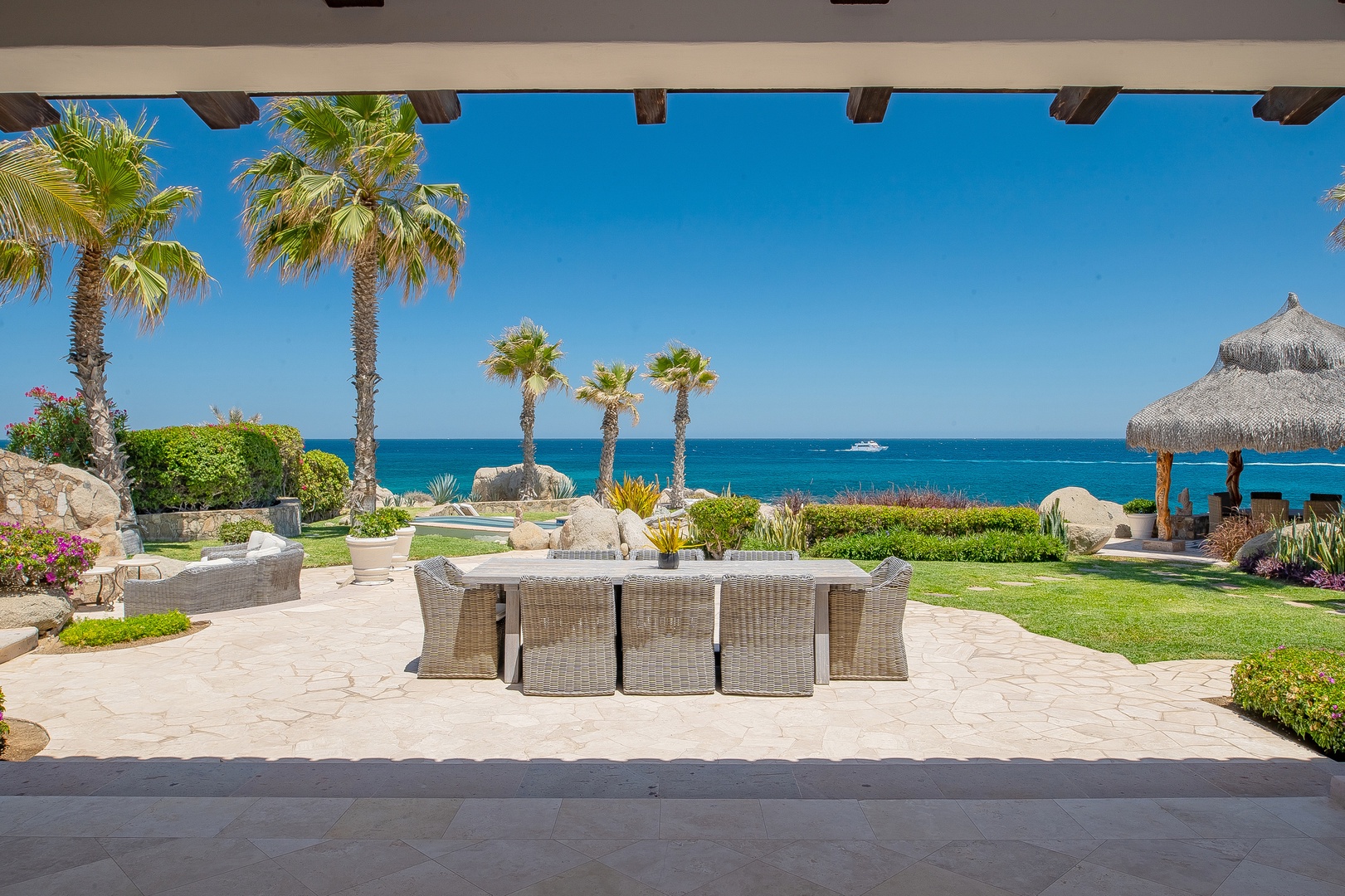 Spectacular oceanfront terrace with tropical palms and pristine waters stretching endlessly before this luxury beachside resort.