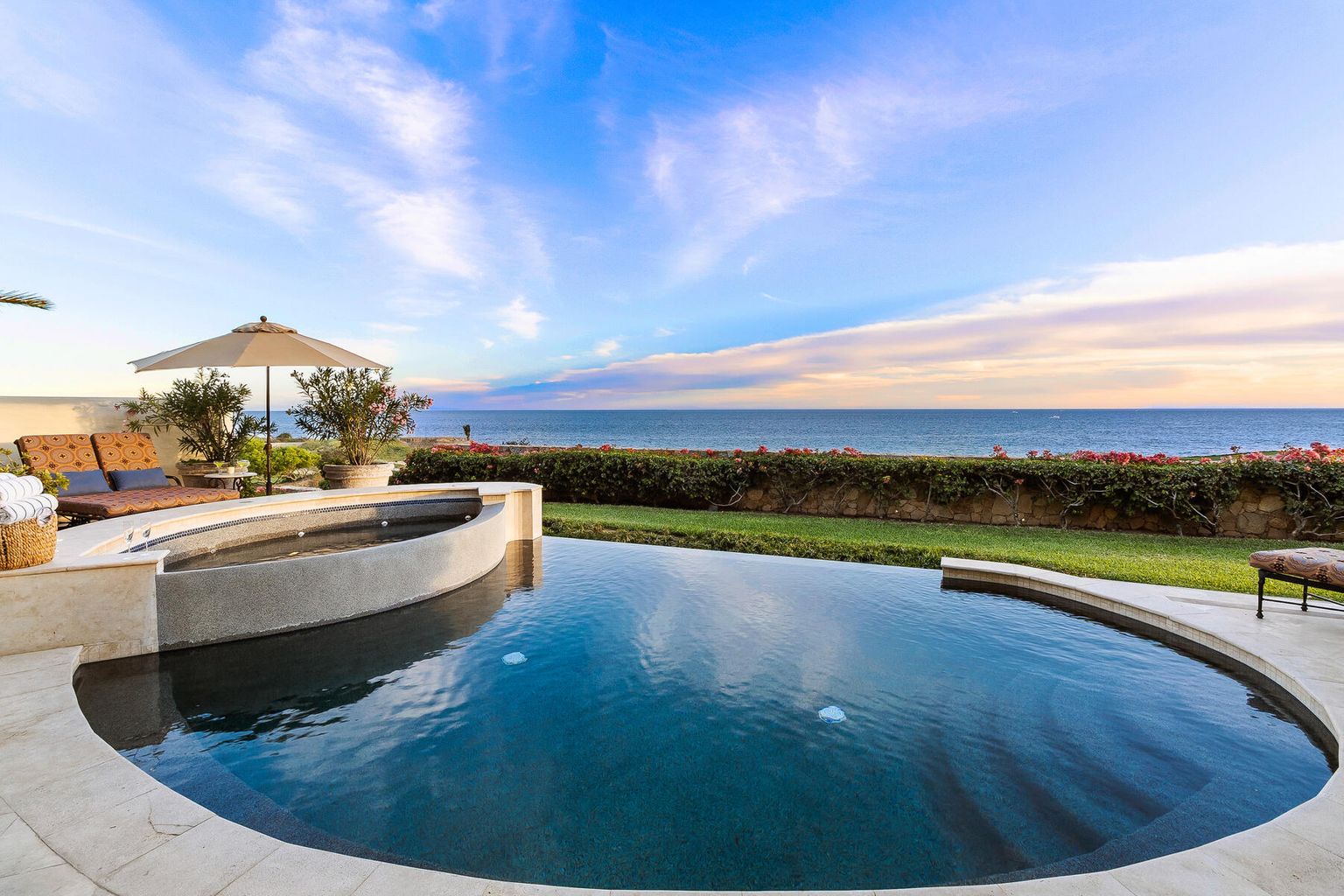 Stunning ocean views stretch across the horizon from your private pool and hot tub, framed by manicured lawns and vibrant coastal gardens—a serene retreat for soaking in paradise.