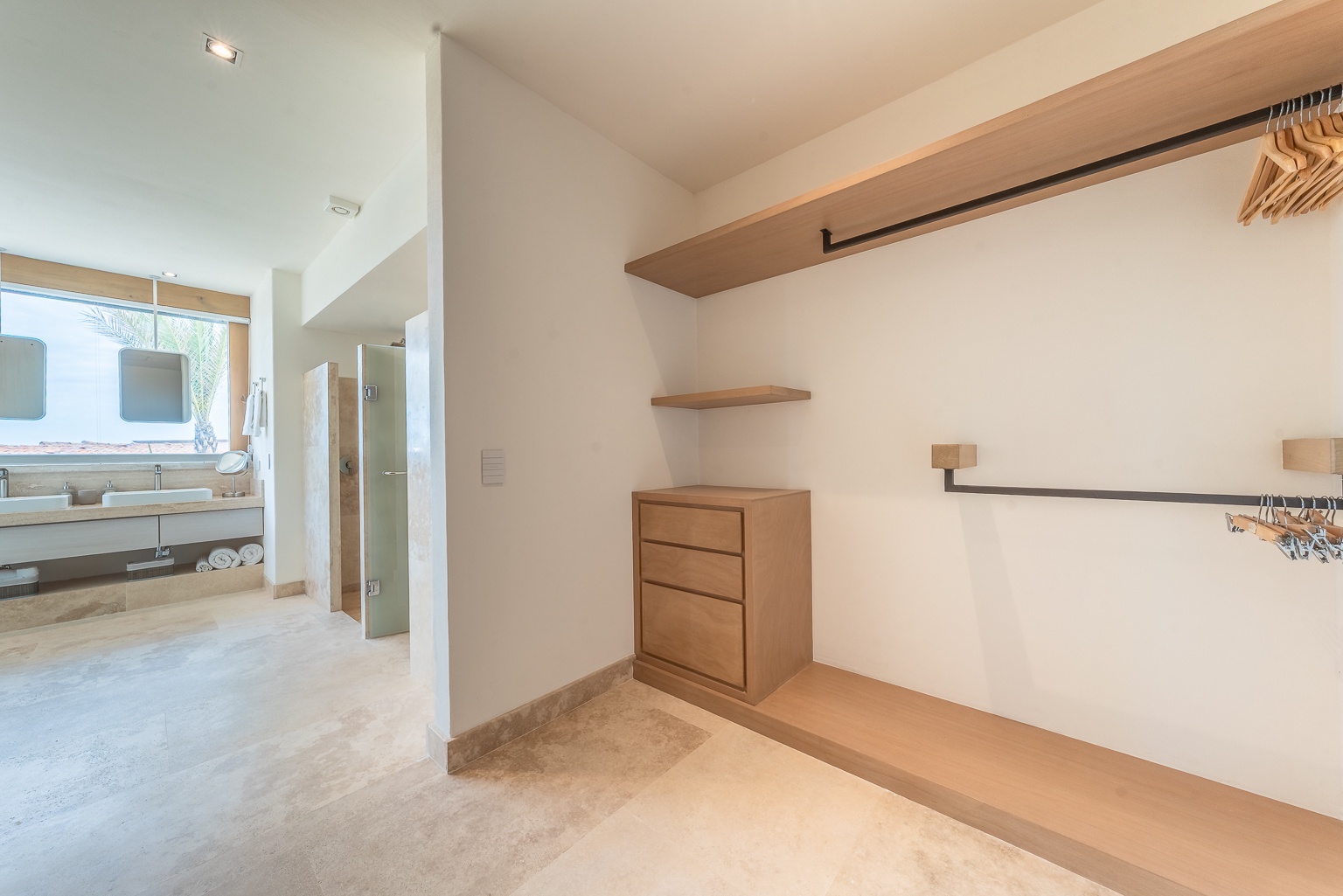 Step into your spacious walk-in closet, outfitted with warm wood shelving and hanging space to keep your belongings organized throughout your stay, seamlessly connecting to a bright en-suite bathroom.