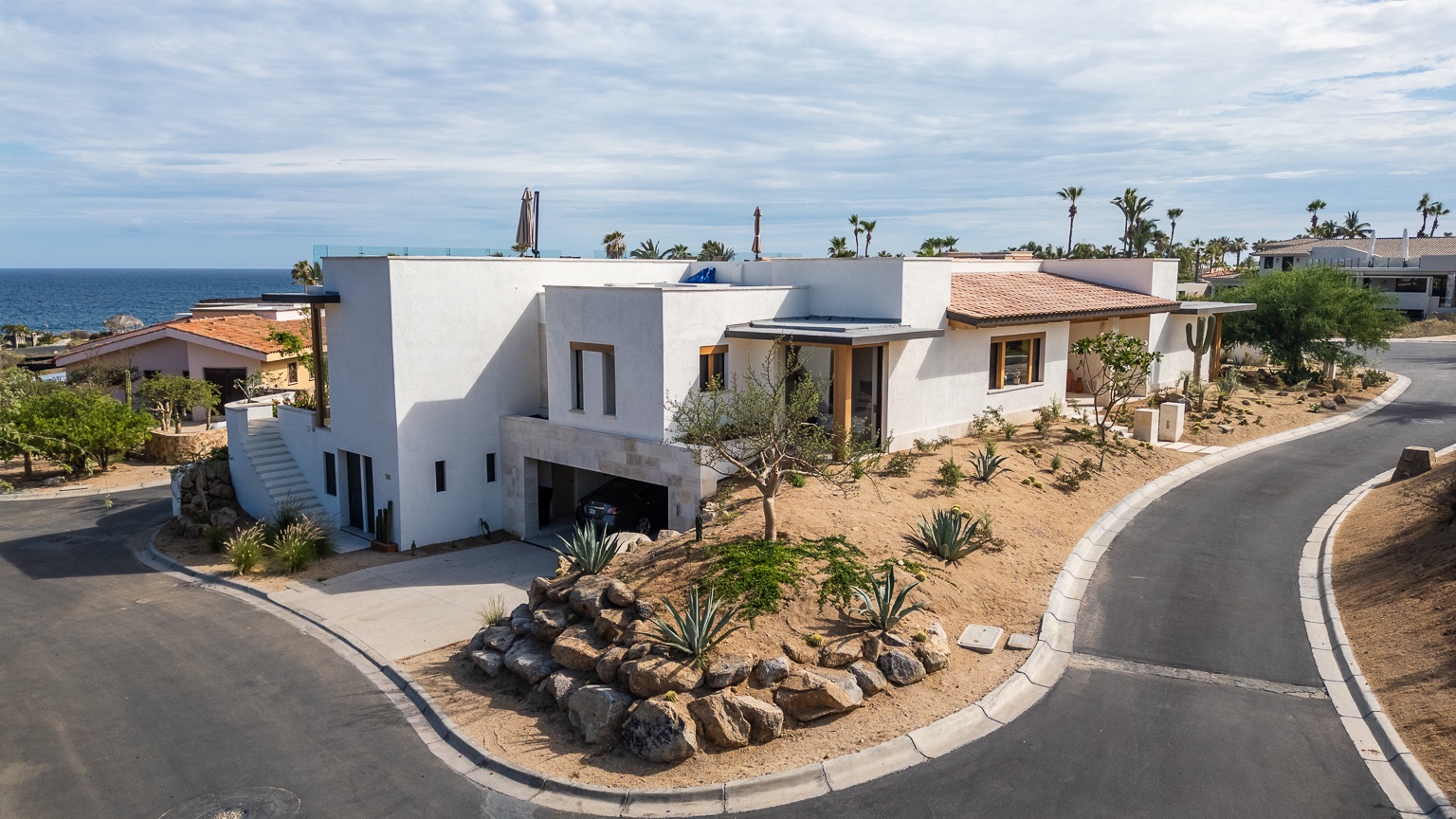 Stunning beachfront property nestled in a serene coastal neighborhood with ocean views, desert landscaping, and modern architecture combining traditional and contemporary design elements.