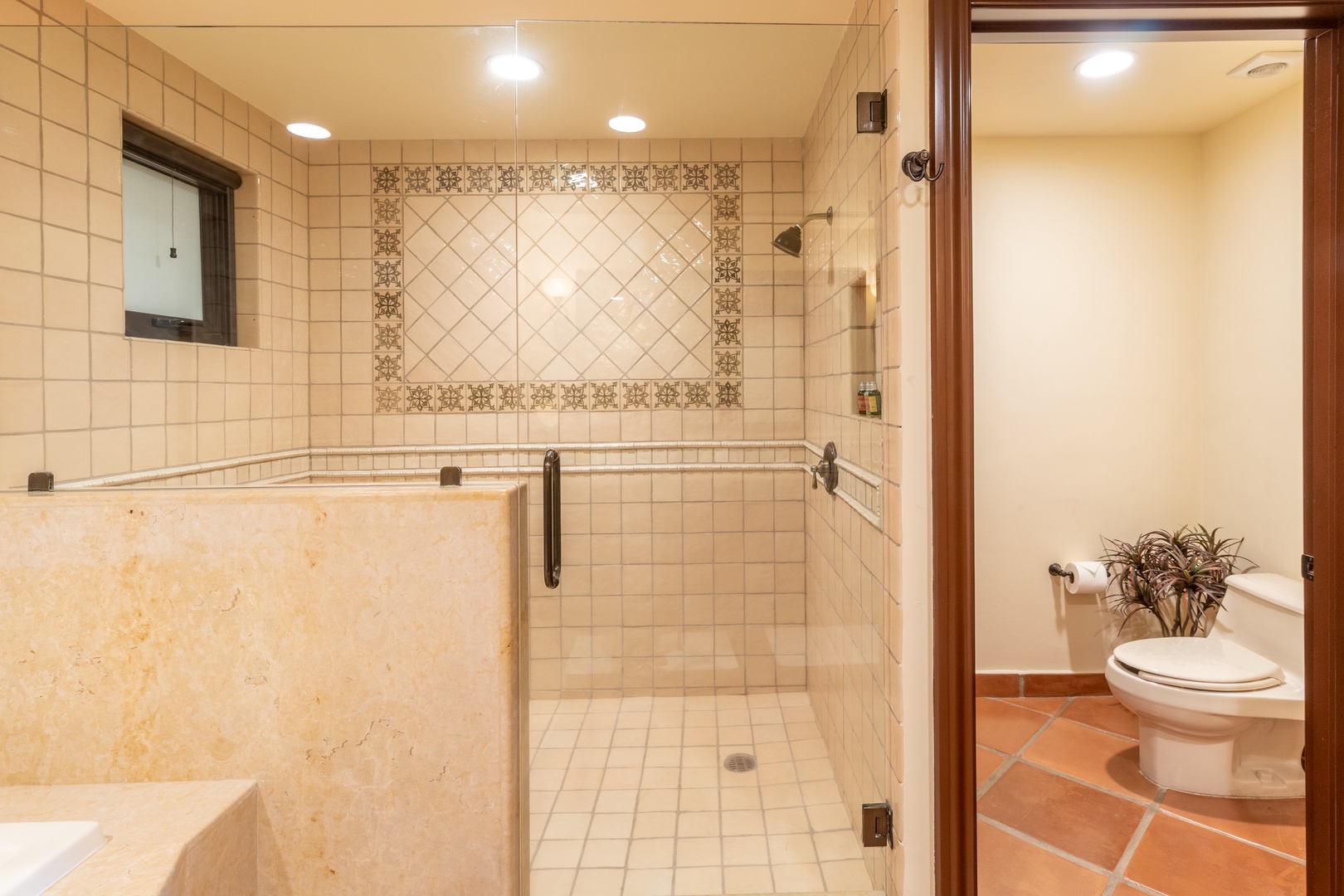 Step into your private spa-like retreat with an elegant tiled walk-in shower featuring decorative accent tiles and a soaking tub for ultimate relaxation.