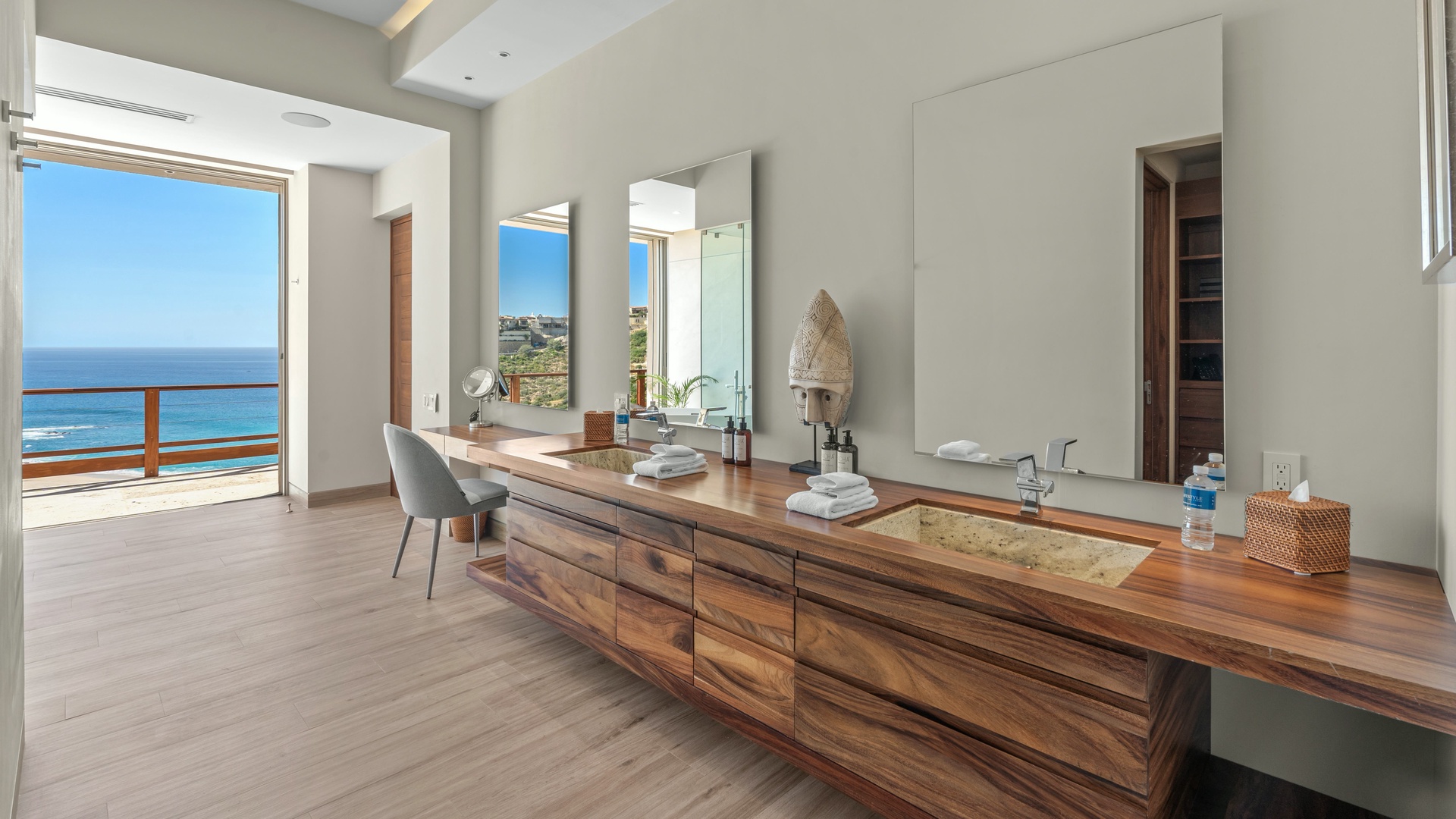 Step into your luxurious bathroom where warm wood tones meet serene ocean views. The stunning double vanity opens to your private balcony overlooking endless blue waters.