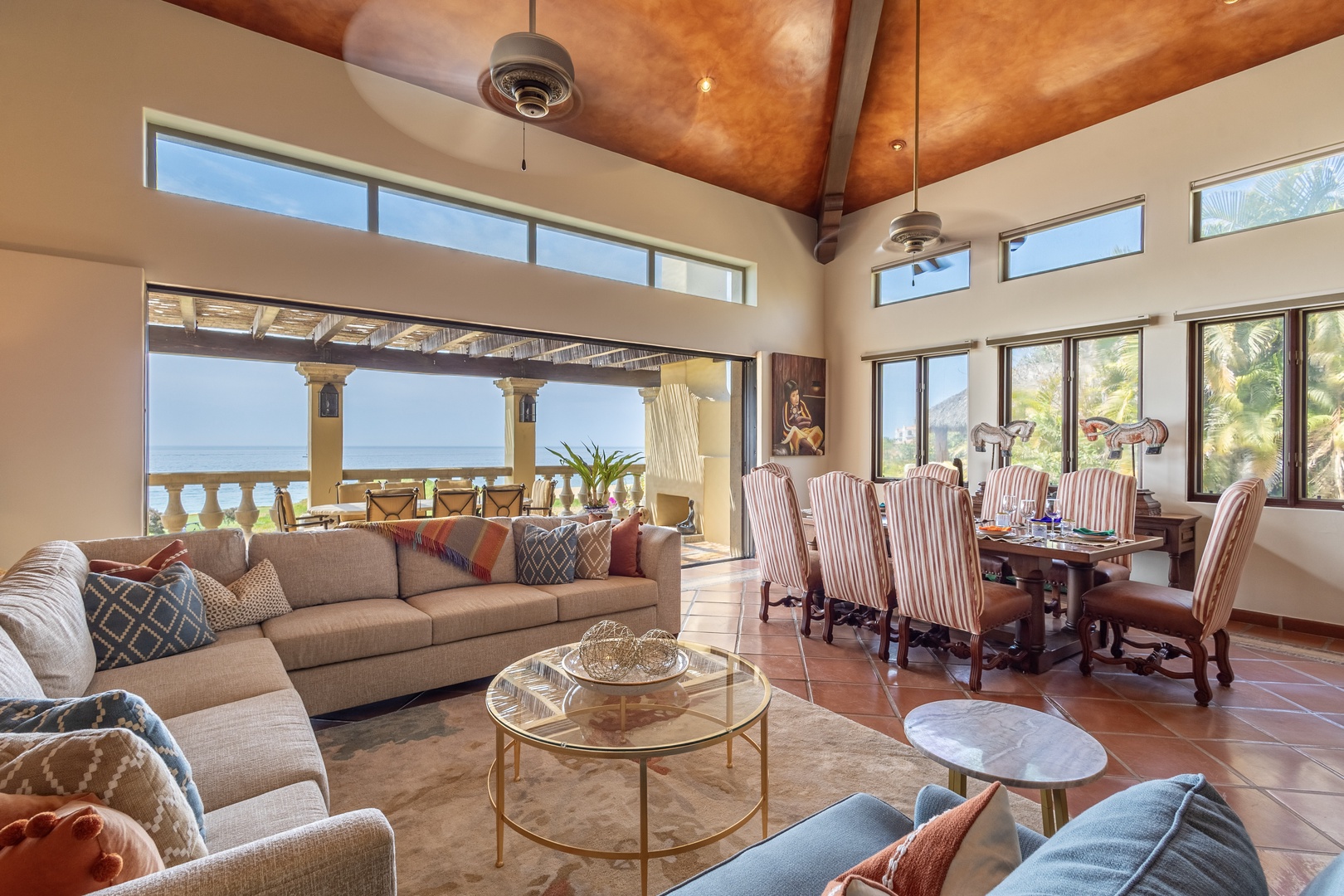 Sink into the plush sectional and soak in breathtaking sea views through soaring windows. This bright, open living and dining space invites relaxation with its vaulted ceiling, tropical breezes, and seamless indoor-outdoor flow.